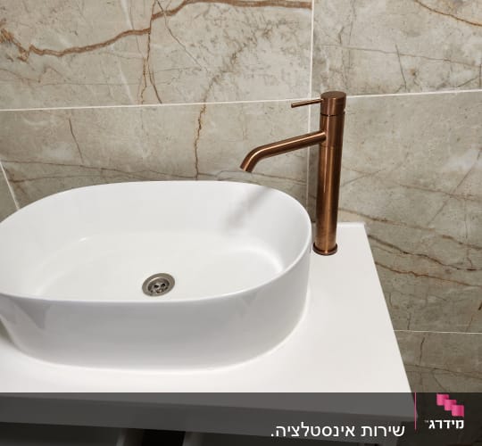 כיור וברז בחדר אמבטיה עם אריחי קיר.